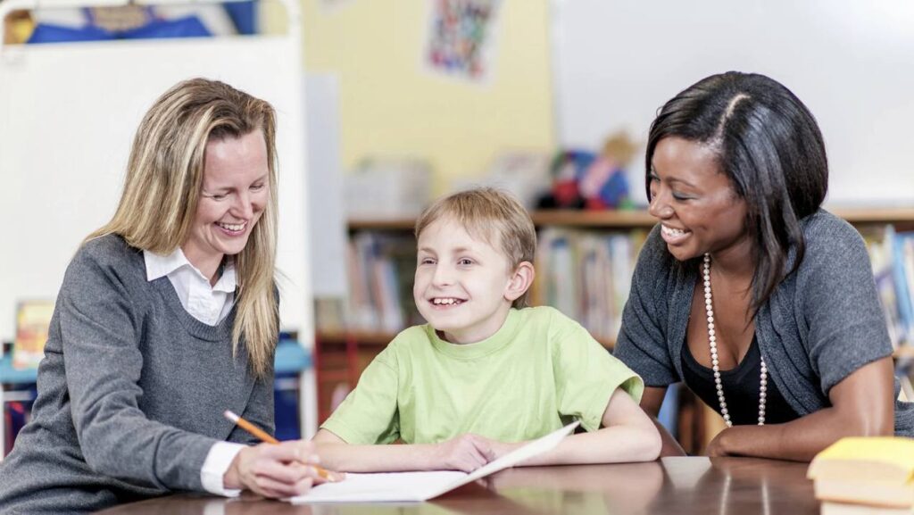 two teachers working with a student in a classroom