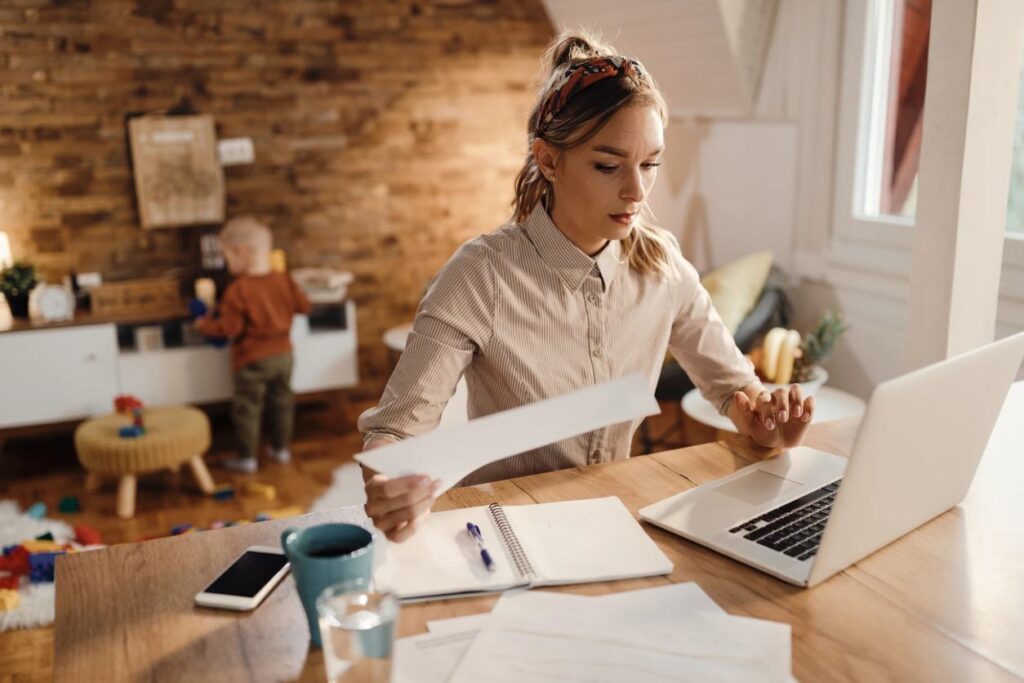 woman looking through documents and on her laptop