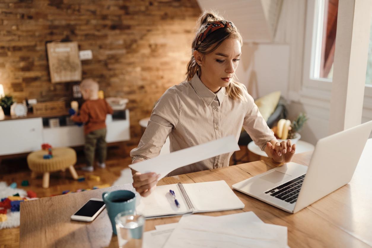 woman looking through documents and on her laptop